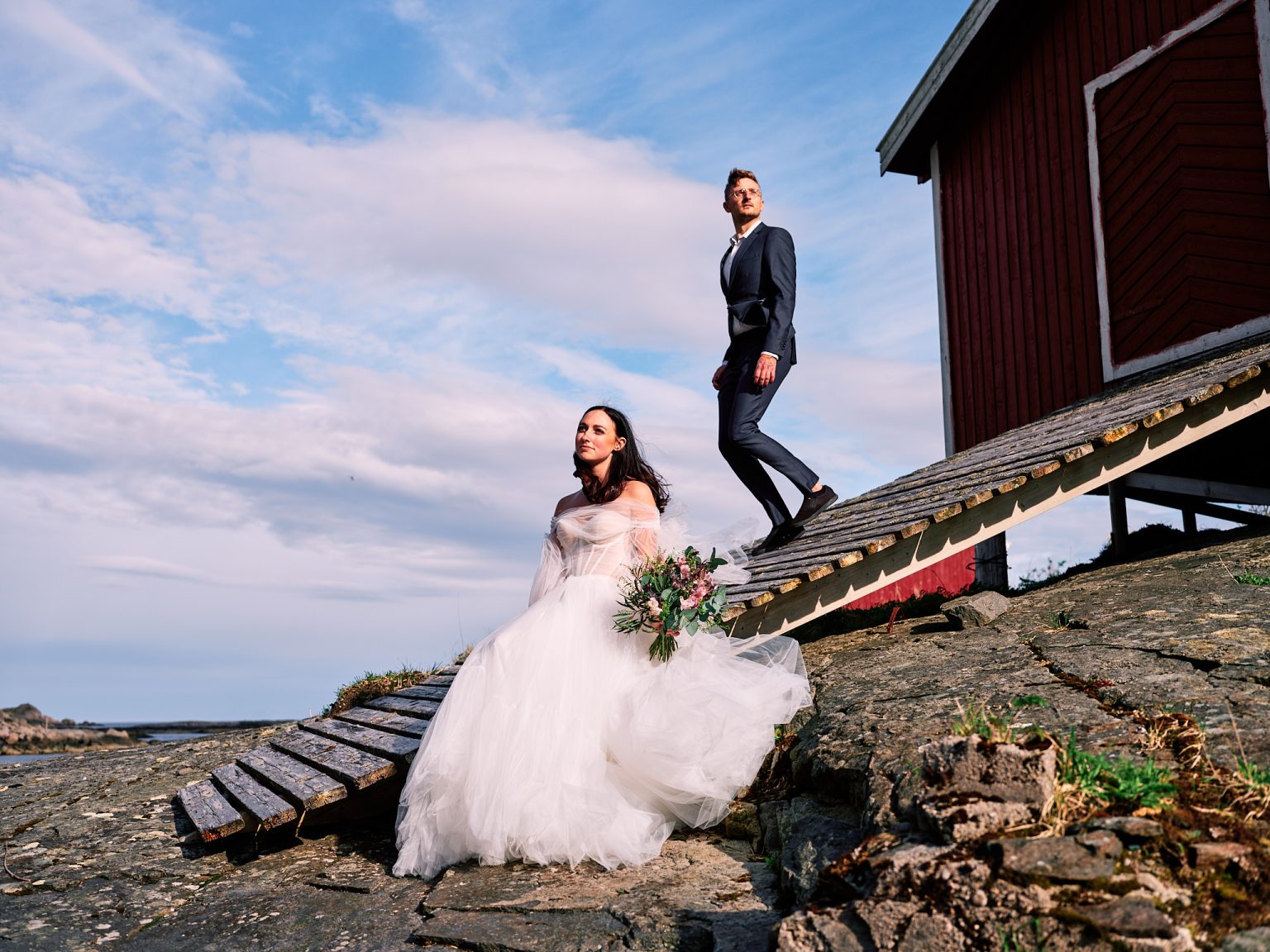 The couple on a slipway by red Lofoten fishing cabins
