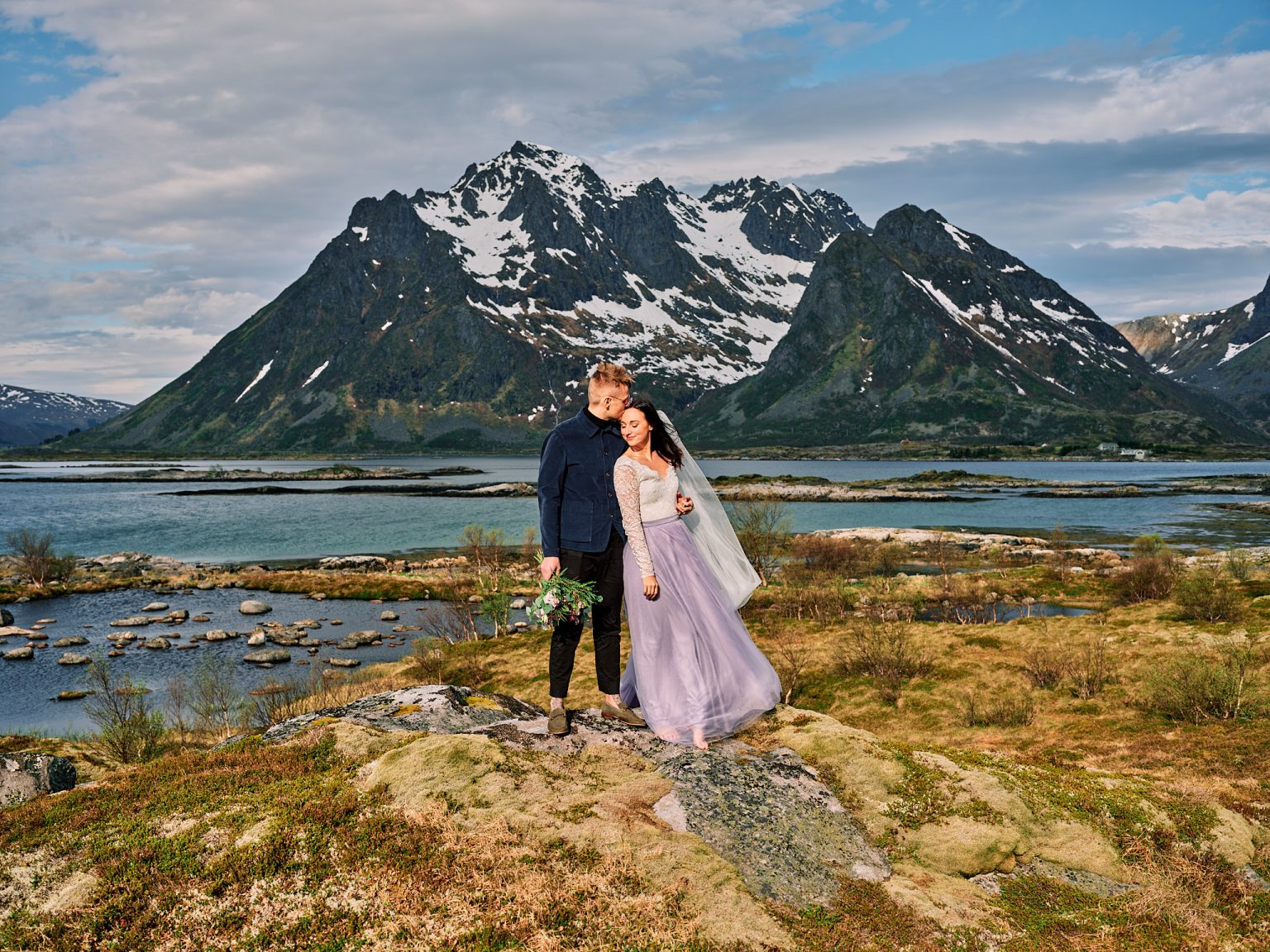 The couple on the shore below the snow peaks of Lofoten