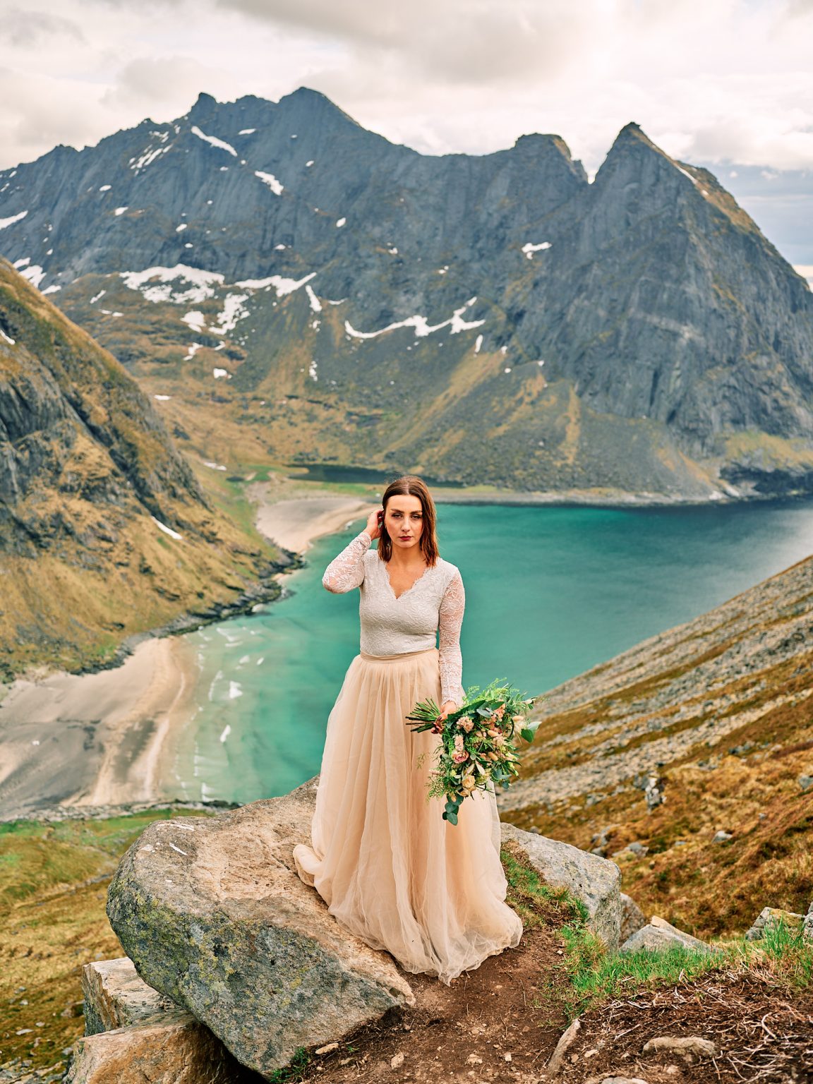 Bride with her bouquet on Ryten, Kvalvika beach below