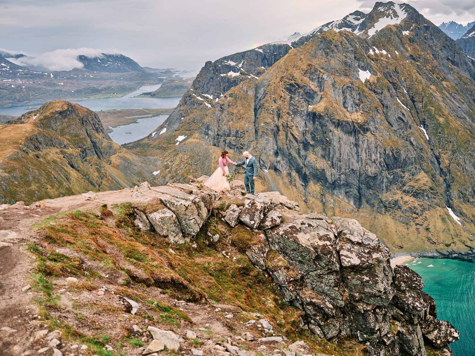 Ine and Jimmy tiny on a Ryten outcrop above the Lofoten beaches