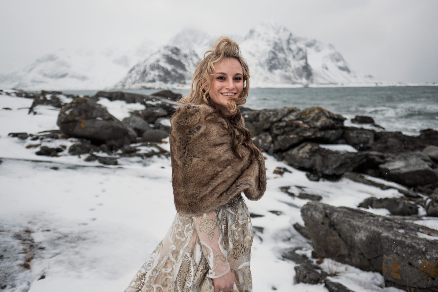 Jamie in a fur wrap on a snowy Lofoten shore, a winter elopement in Norway
