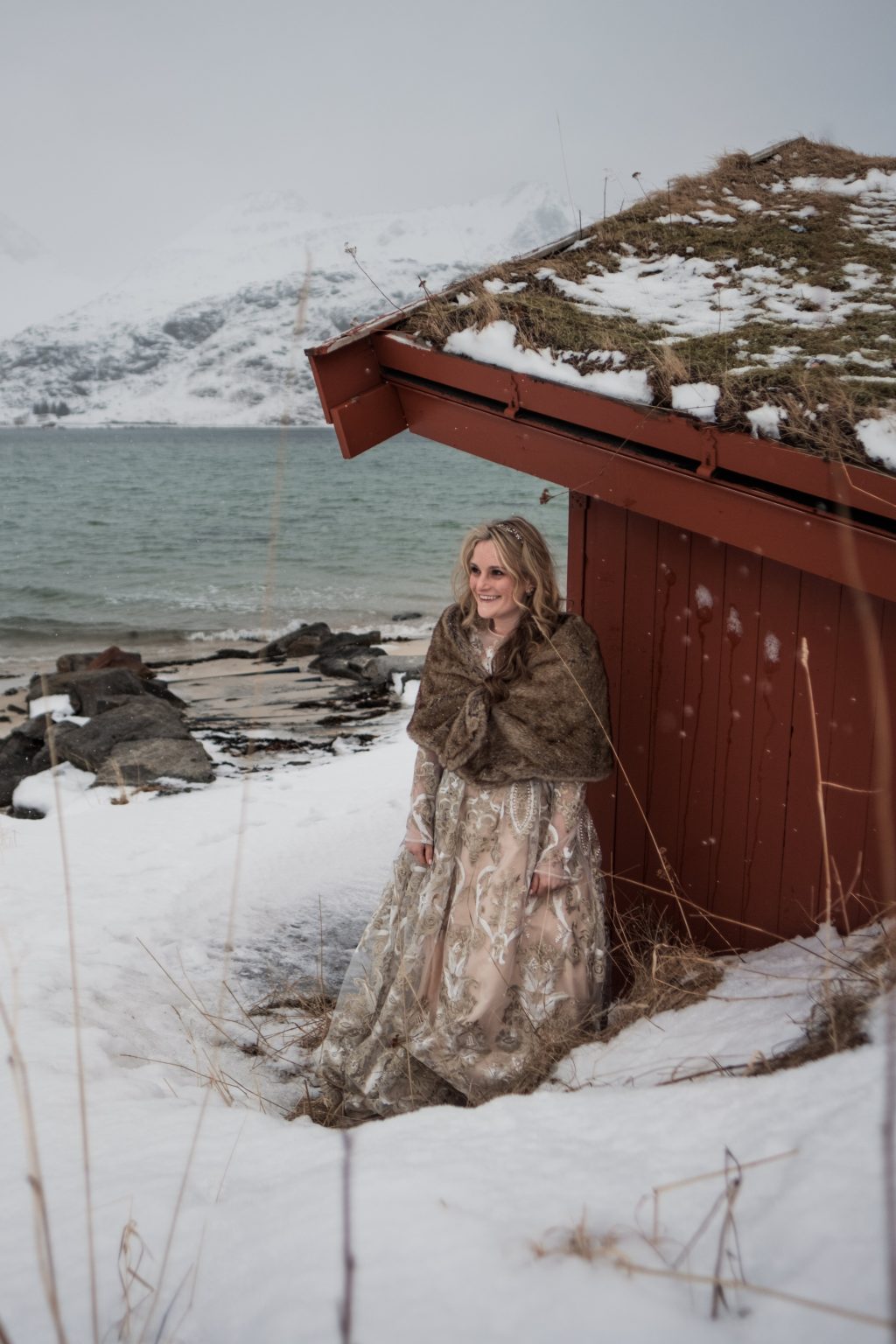 Jamie by a turf-roofed hut in the snow, Lofoten winter elopement