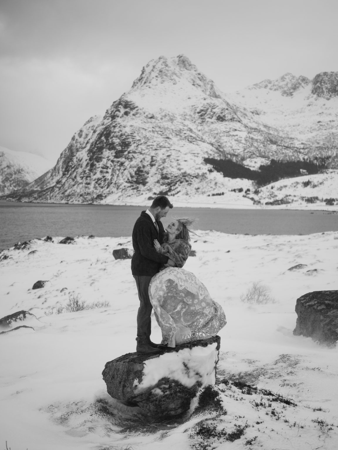 The couple tiny beneath a huge snowy peak, a Lofoten winter elopement