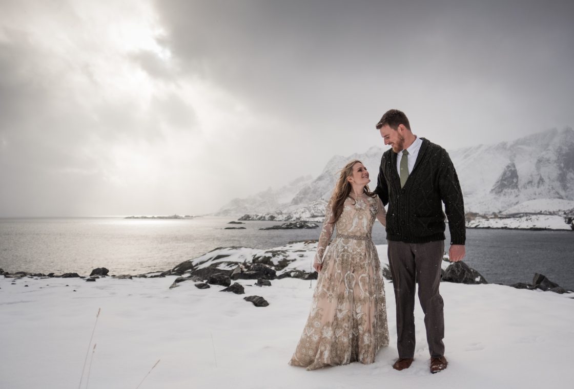 Jamie and Christopher on the shore in dramatic winter light, a Lofoten winter elopement