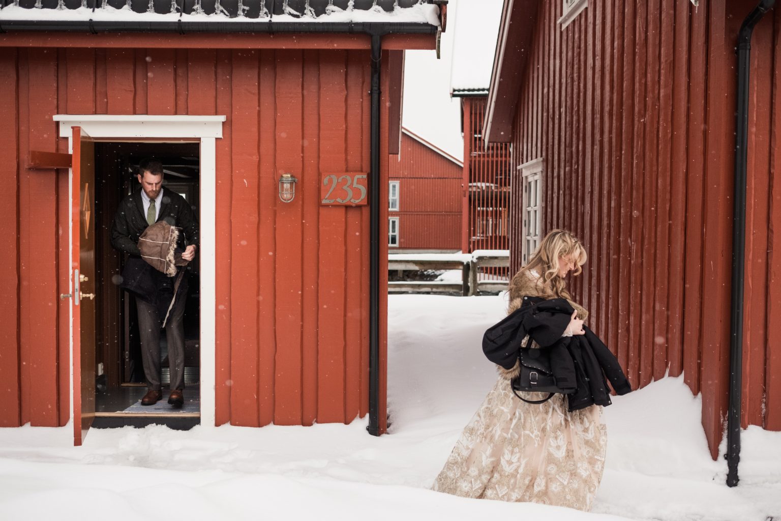 Jamie and Christopher in the doorway of a red cabin, Lofoten in winter
