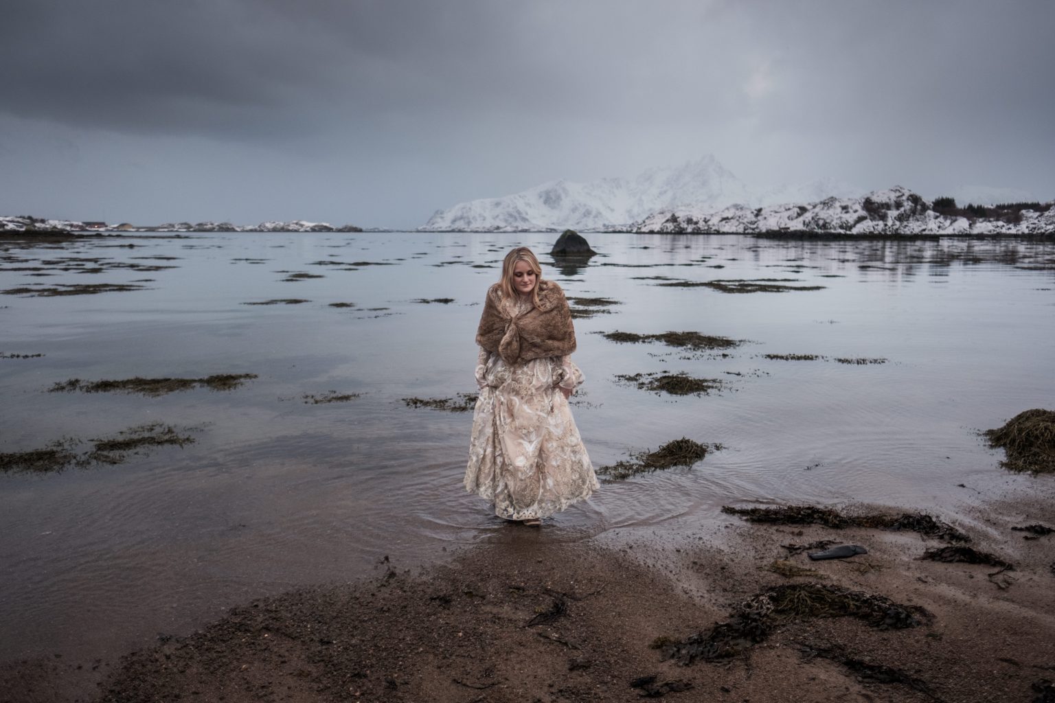 Embracing at the water's edge below the peaks, Lofoten in winter