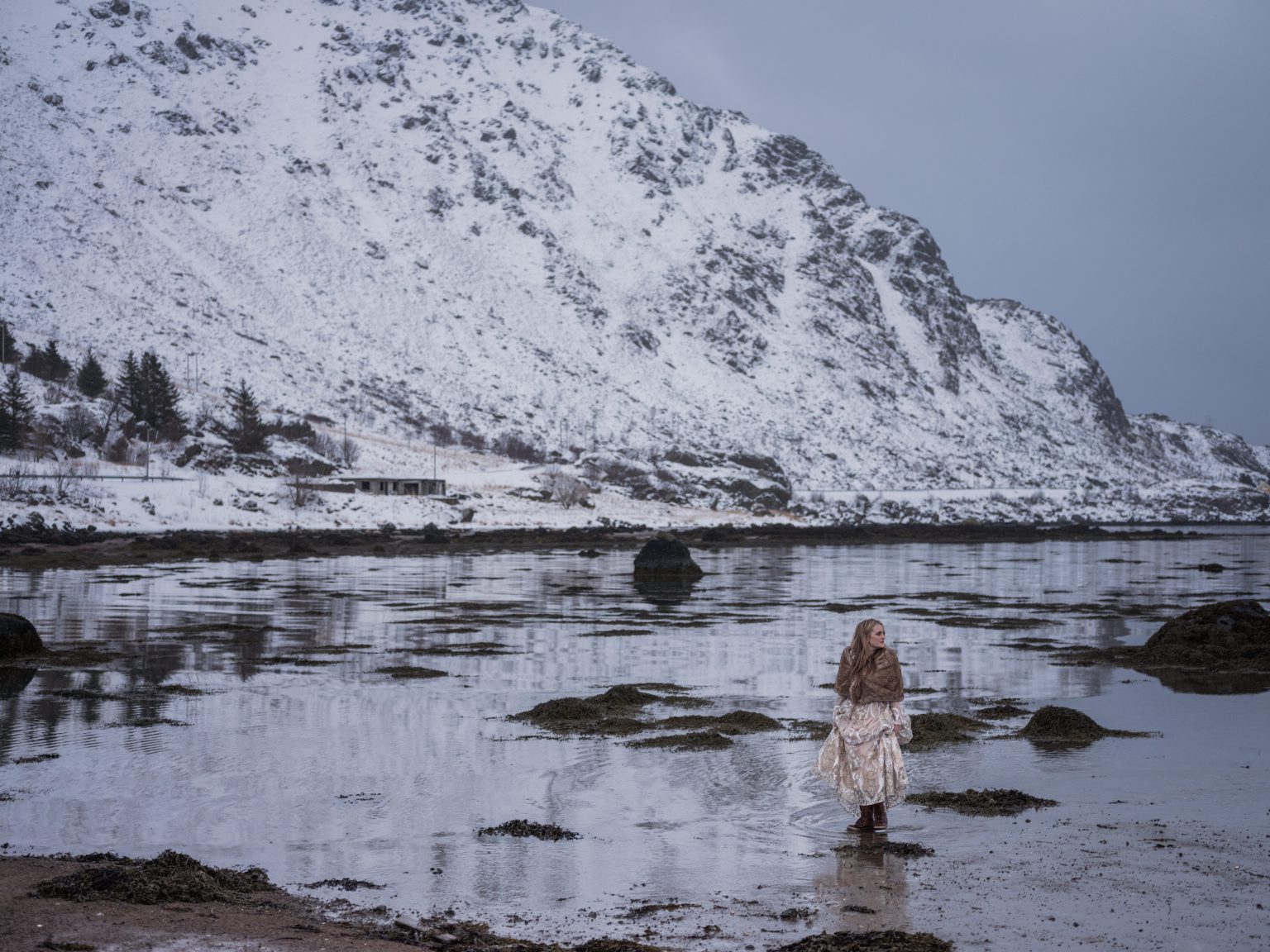 The bride alone in a vast snowy Lofoten landscape, a winter elopement