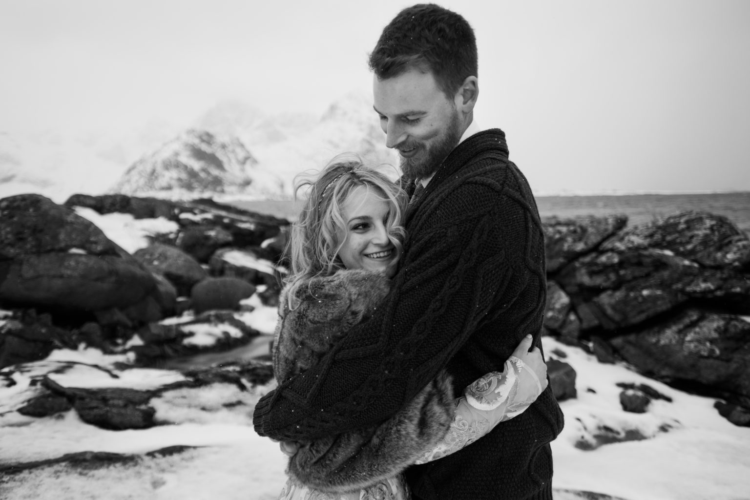 The couple embracing on a snowy shore, a Lofoten winter elopement