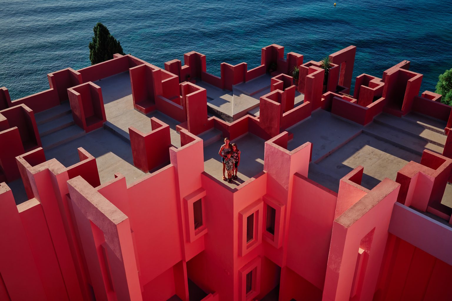 The rooftop maze of La Muralla Roja above the sea, one small figure among the pink walls