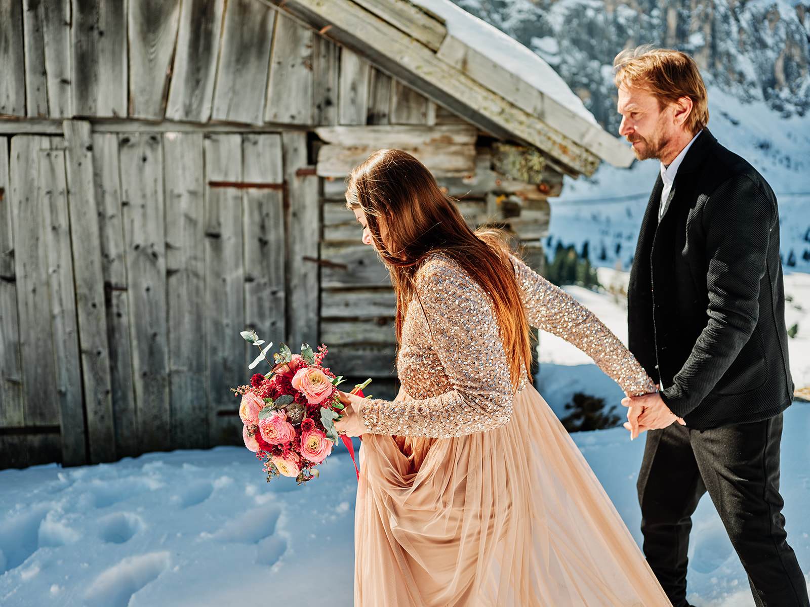 Bride and groom laughing with the bouquet in the snow at Passo Gardena, Dolomites - Nordica Photography