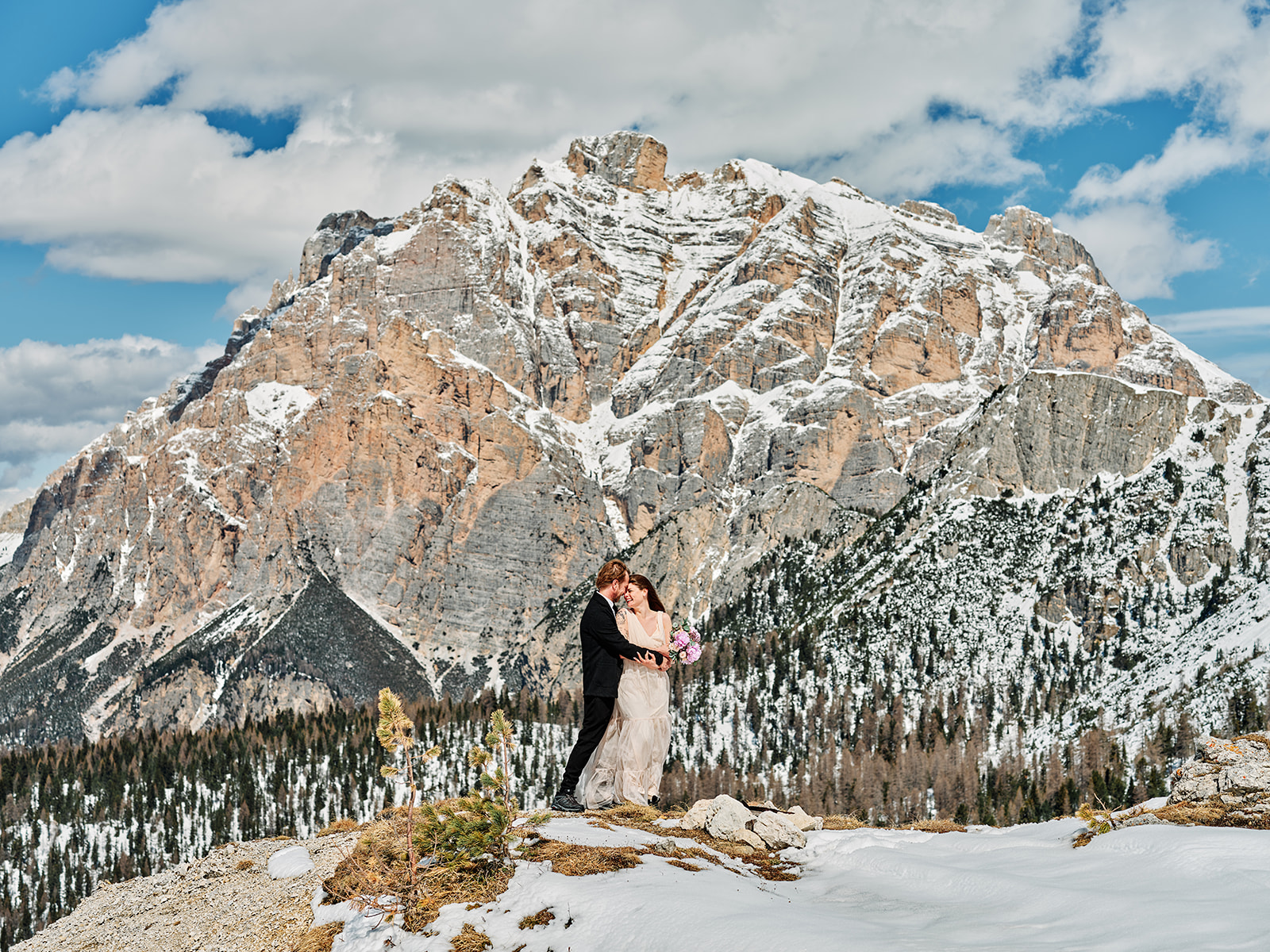 Bride and groom in the snow beneath a Dolomite peak at Passo Gardena winter wedding, Val Gardena - Nordica Photography