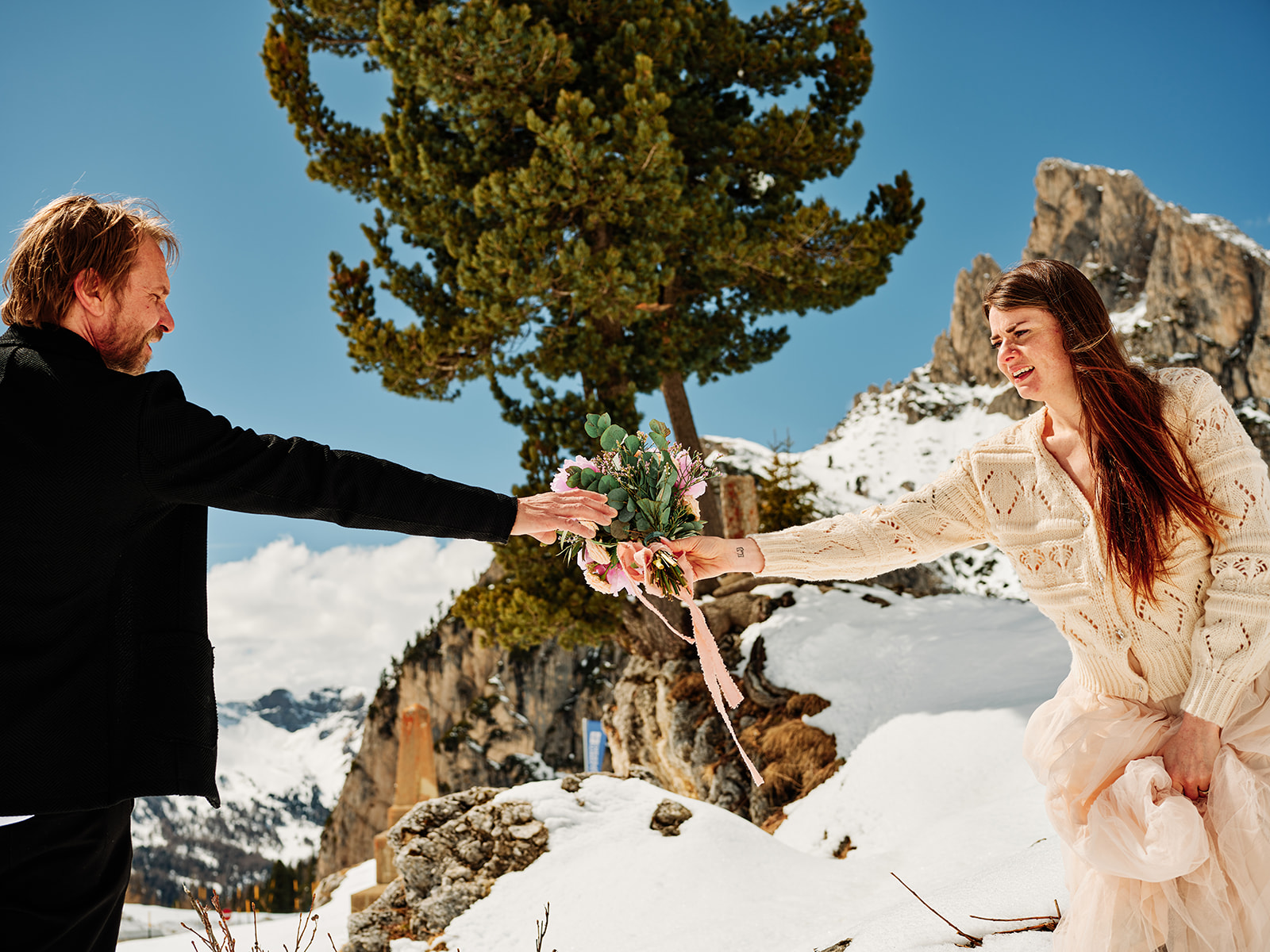 Bride and groom playing in the snow among the pines at Passo Gardena, a Dolomites winter wedding - Nordica Photography