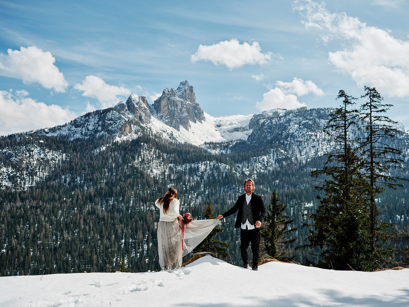 Winter wedding couple on a snowy ridge below jagged Dolomite peaks, Passo Gardena Val Gardena - Nordica Photography