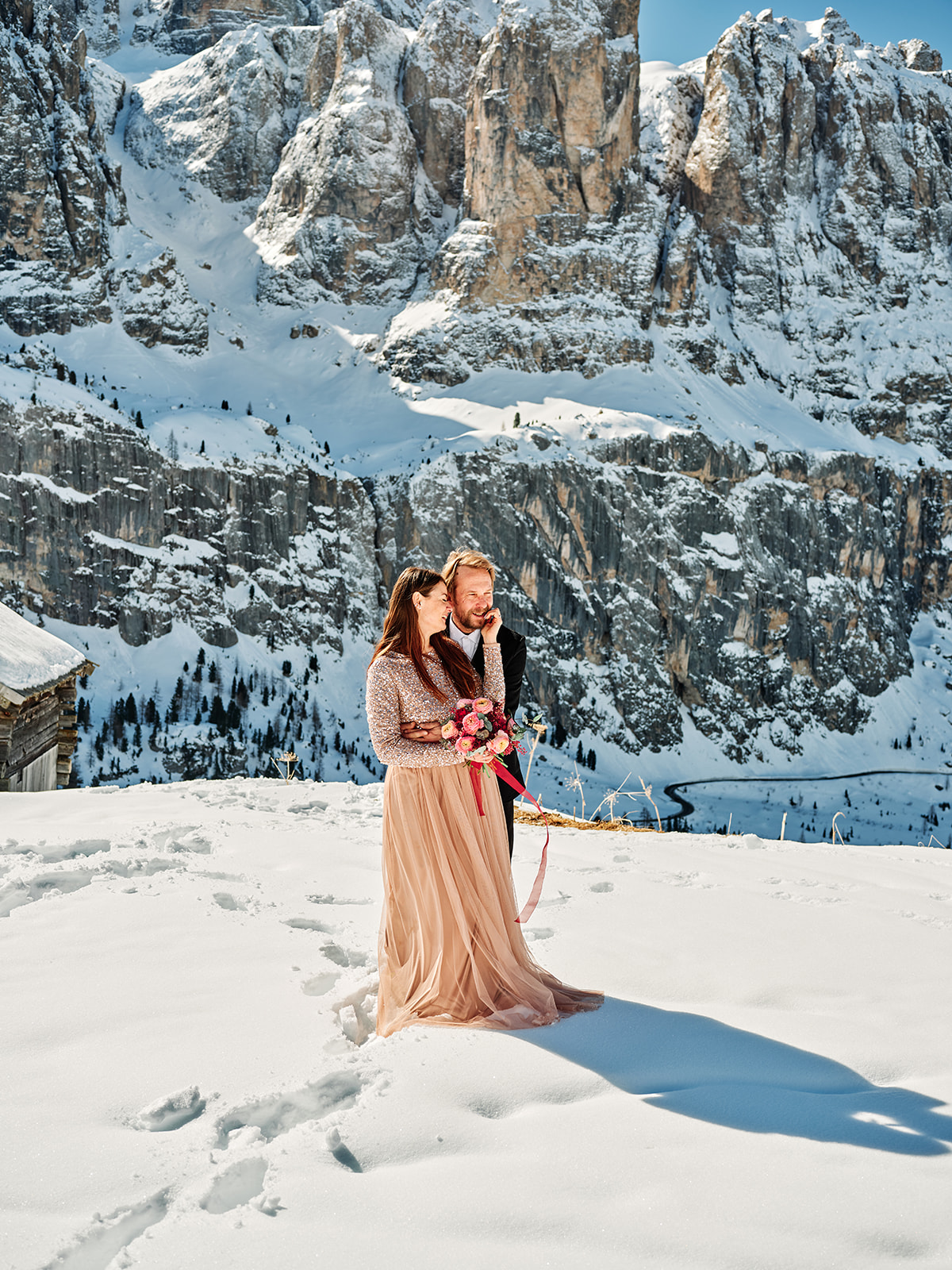 Winter wedding couple above a snowy valley at Passo Gardena, Val Gardena Dolomites - Nordica Photography