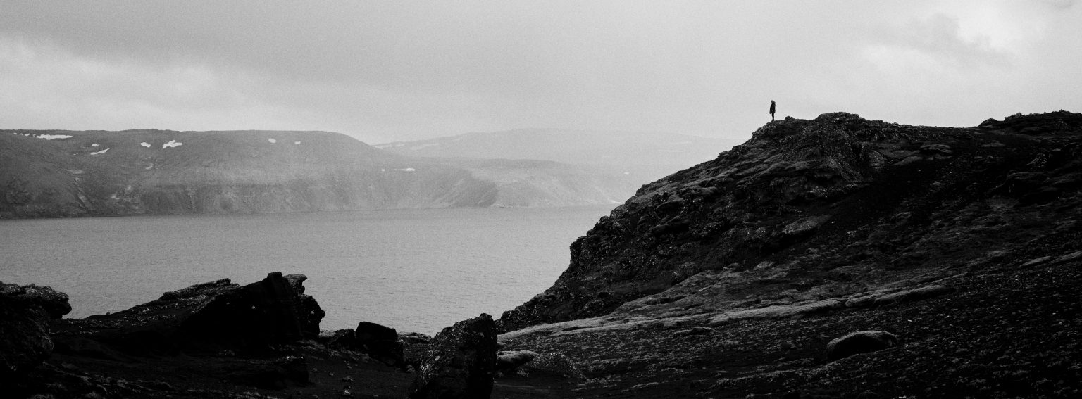 A lone figure on the rocks by the water, Reykjanes