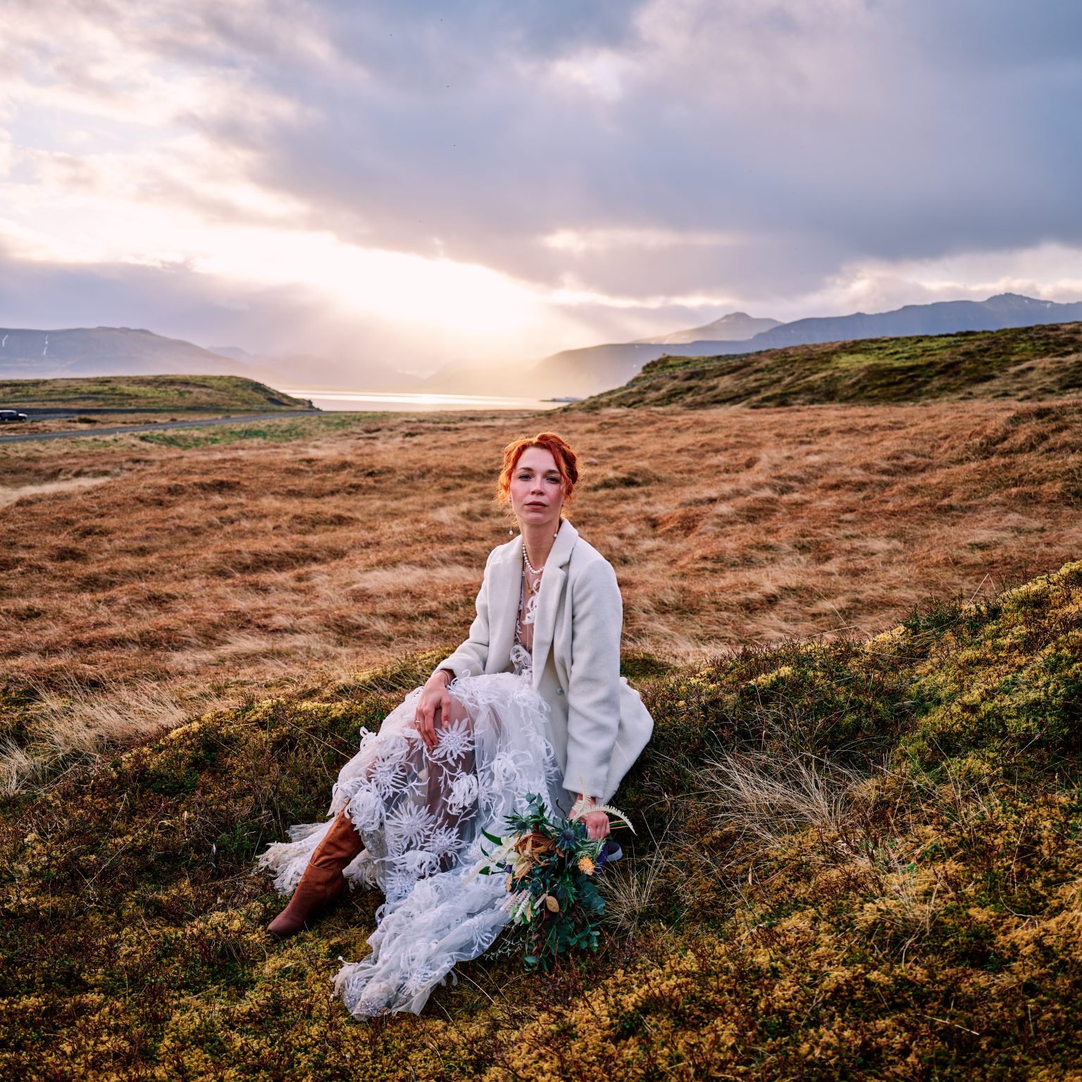 Bride sitting in the golden grass near Kirkjufell at sunrise