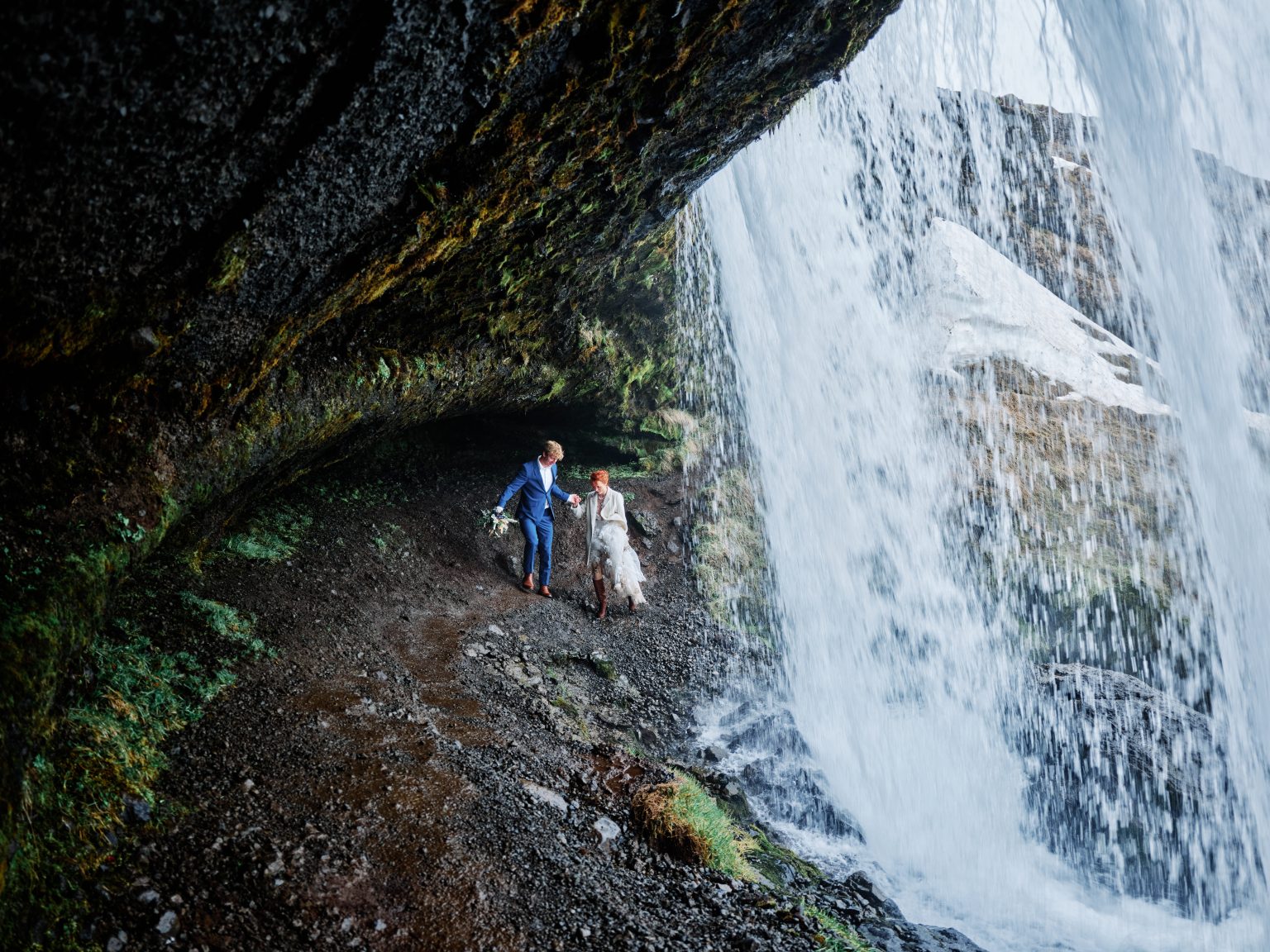Anna and Niklas walking behind a waterfall in Iceland