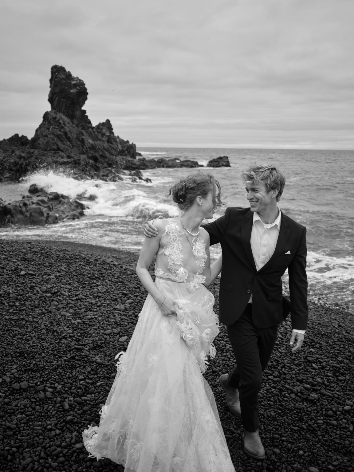 Couple on the black pebble beach below the Arnarstapi cliffs