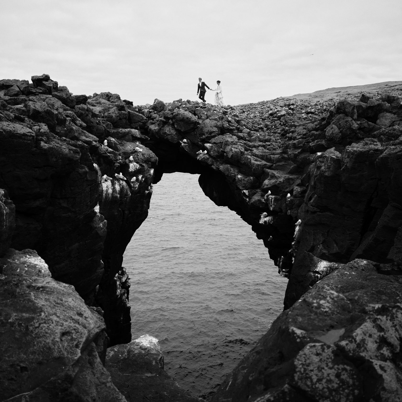 Tiny figures by the Gatklettur arch at Arnarstapi