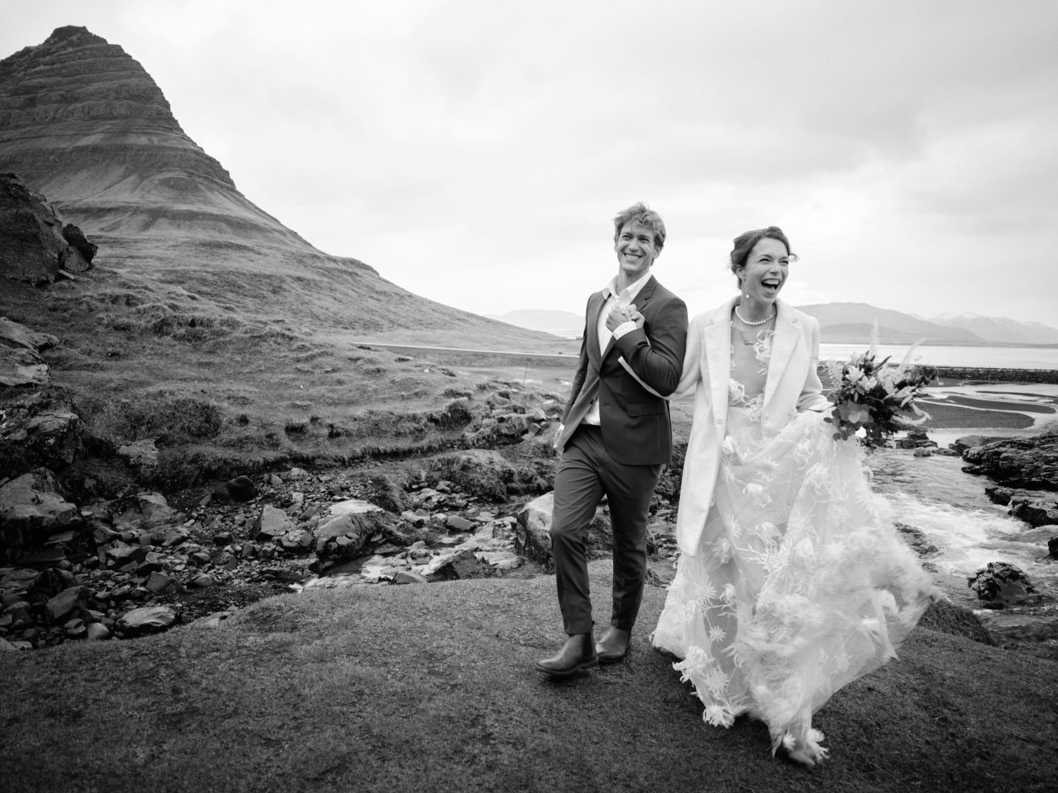 Couple walking below Kirkjufell mountain, black and white