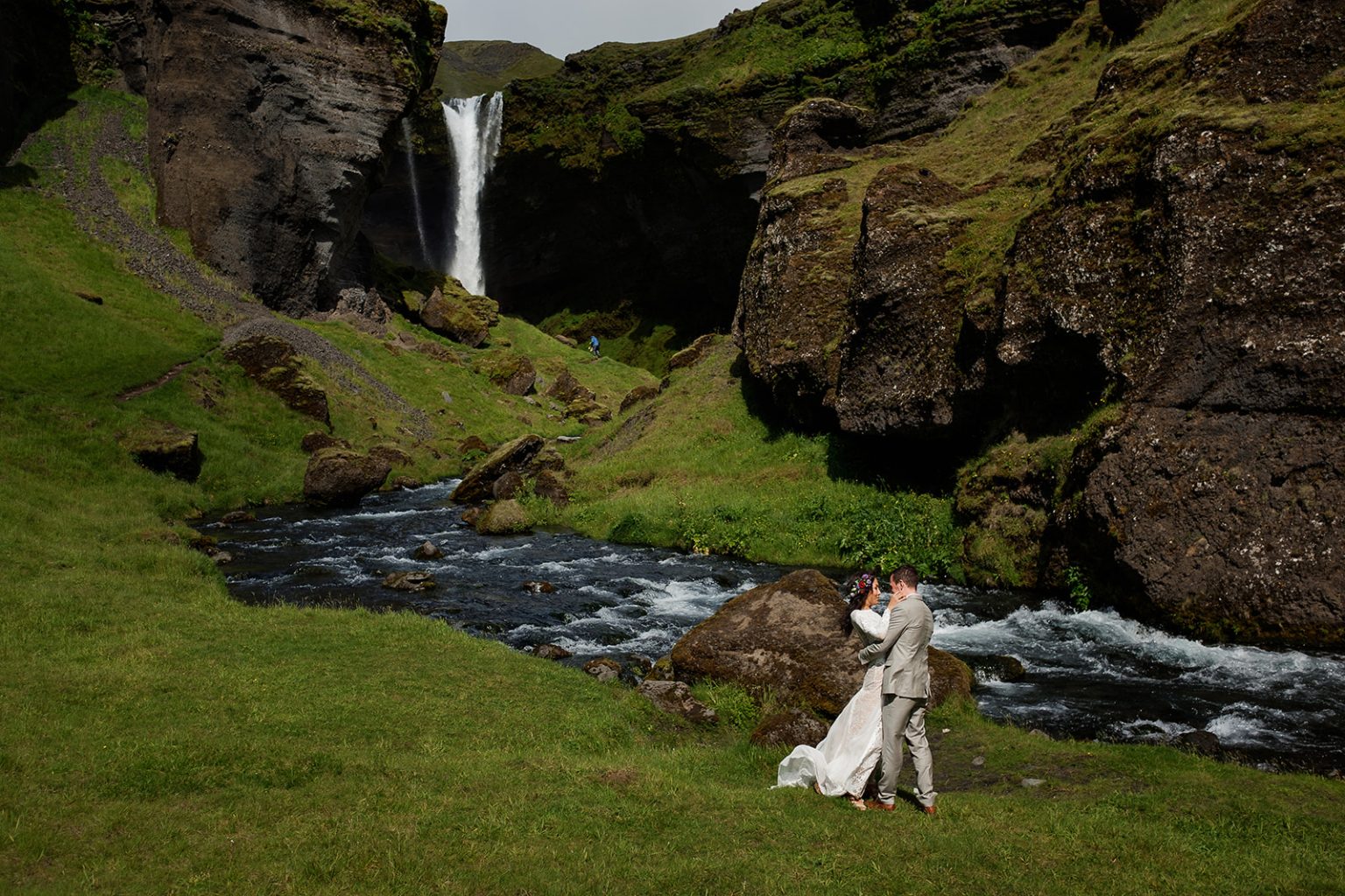 Bride alone in the vast green canyon beneath Kvernufoss during the ceremony, South Iceland elopement