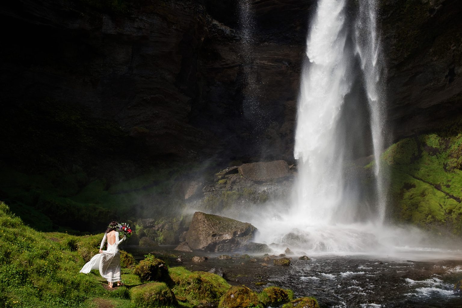 Bride at the foot of Kvernufoss waterfall, South Iceland elopement portrait