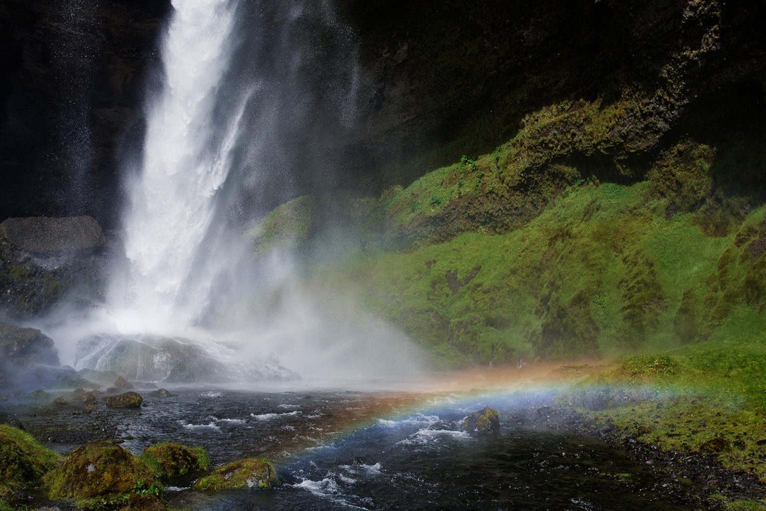 Bride at Kvernufoss with a rainbow across the falls, South Iceland elopement