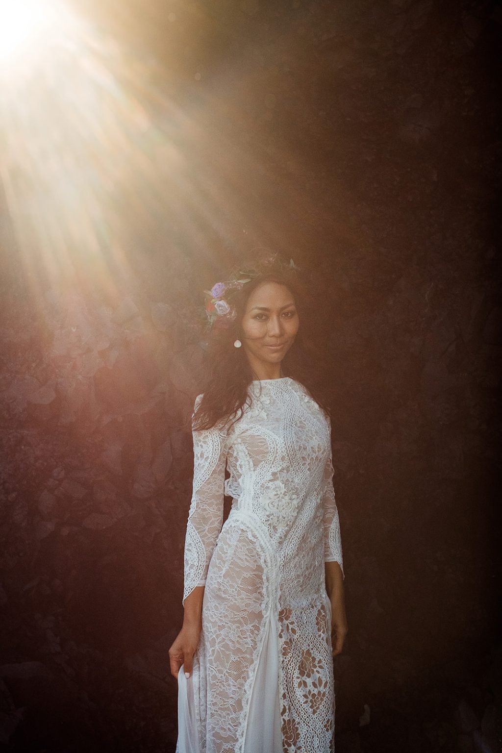 Bride lit by a shaft of light in a Reynisfjara cave, South Iceland elopement portrait
