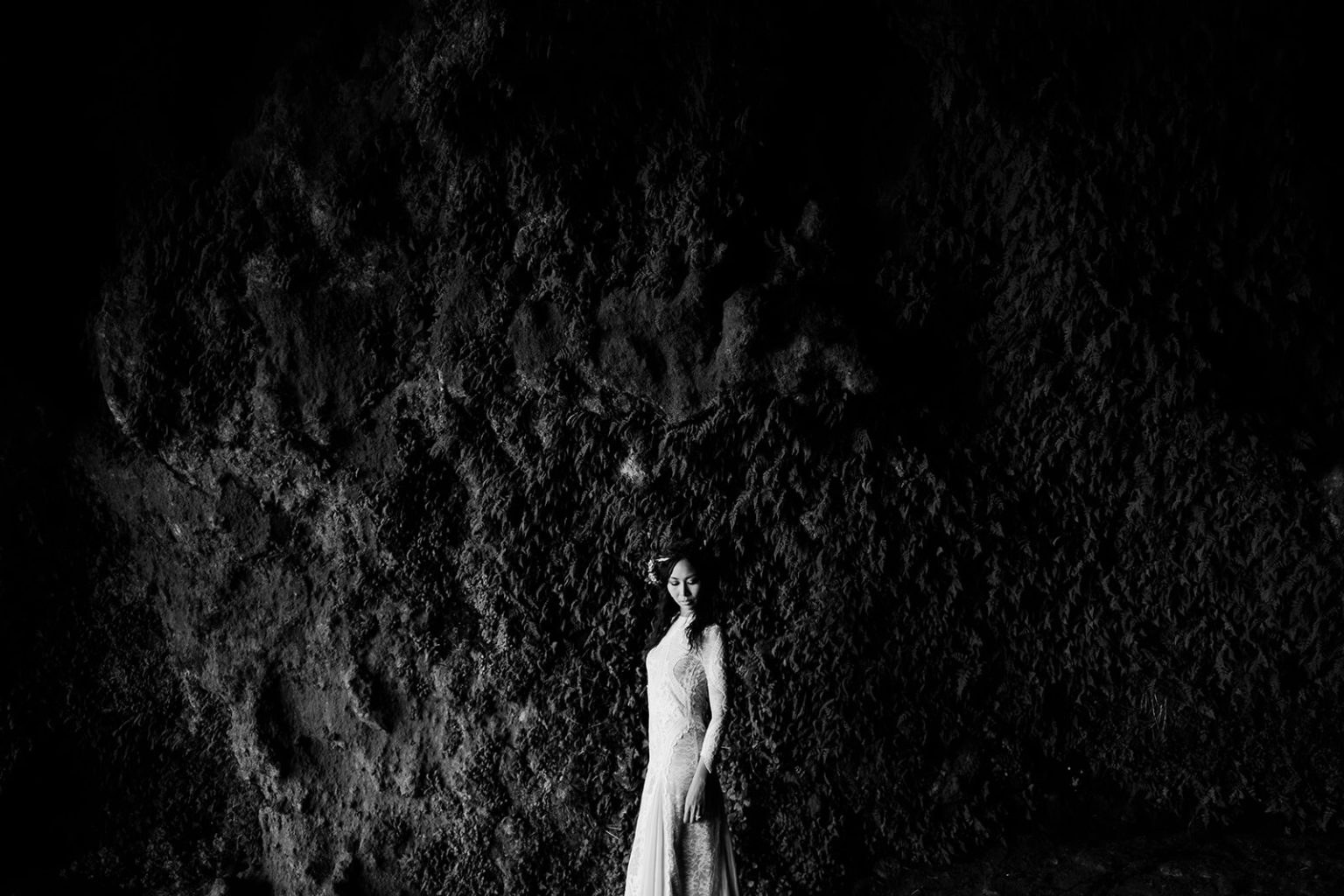 Bride in white against dark green cliffs, South Iceland elopement portrait