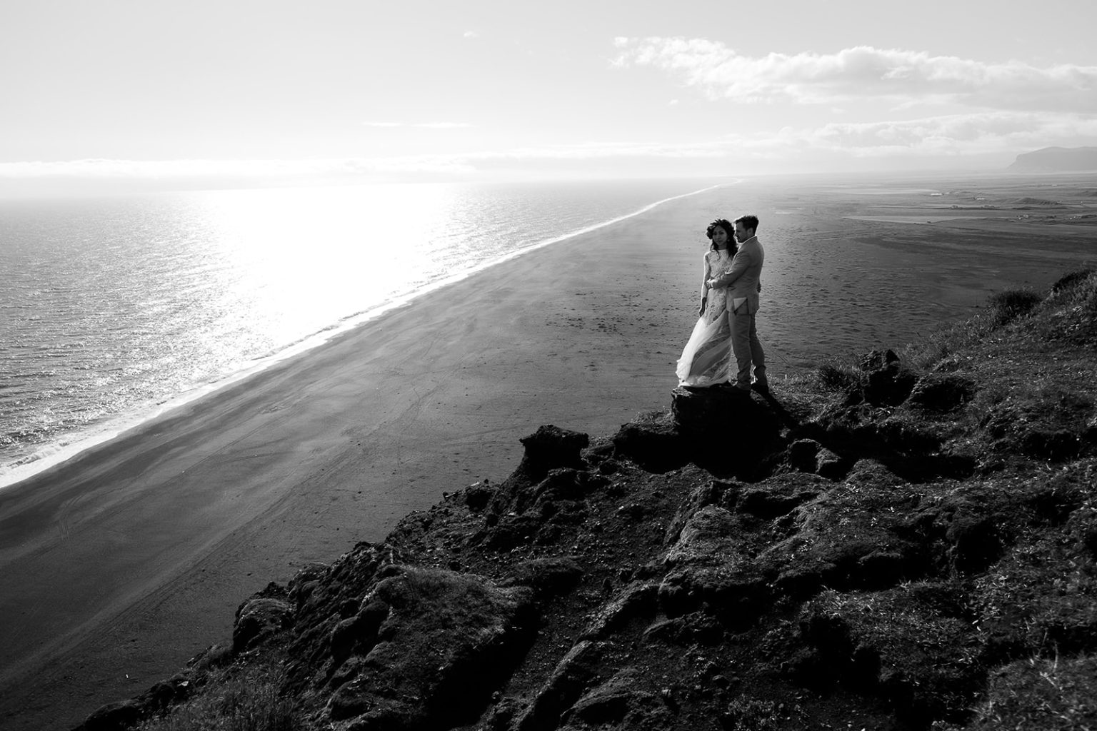 Bride at the cliff edge above the sea at Dyrholaey, South Iceland elopement