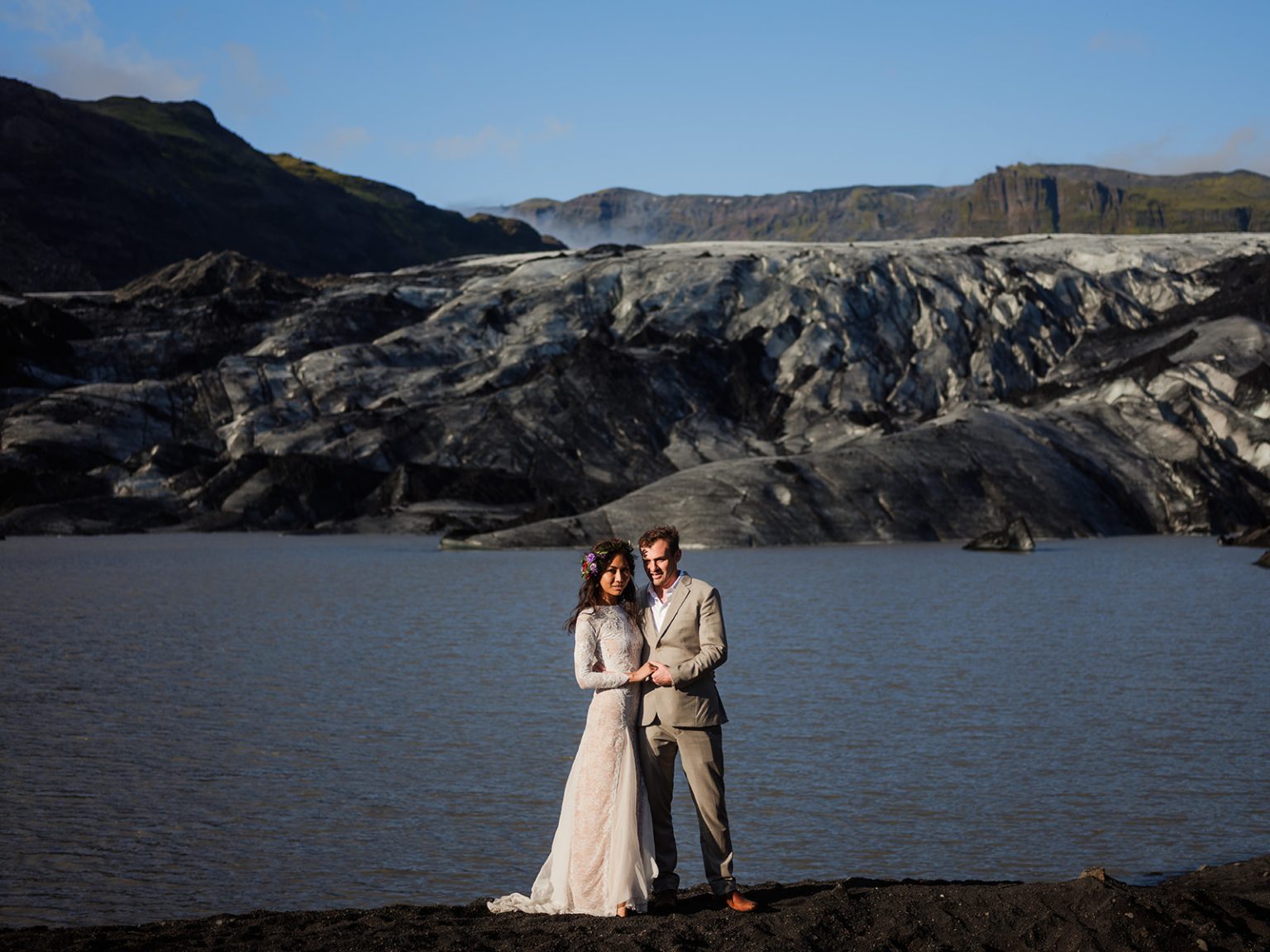 Bride and groom small against Solheimajokull glacier and its lagoon, South Iceland elopement