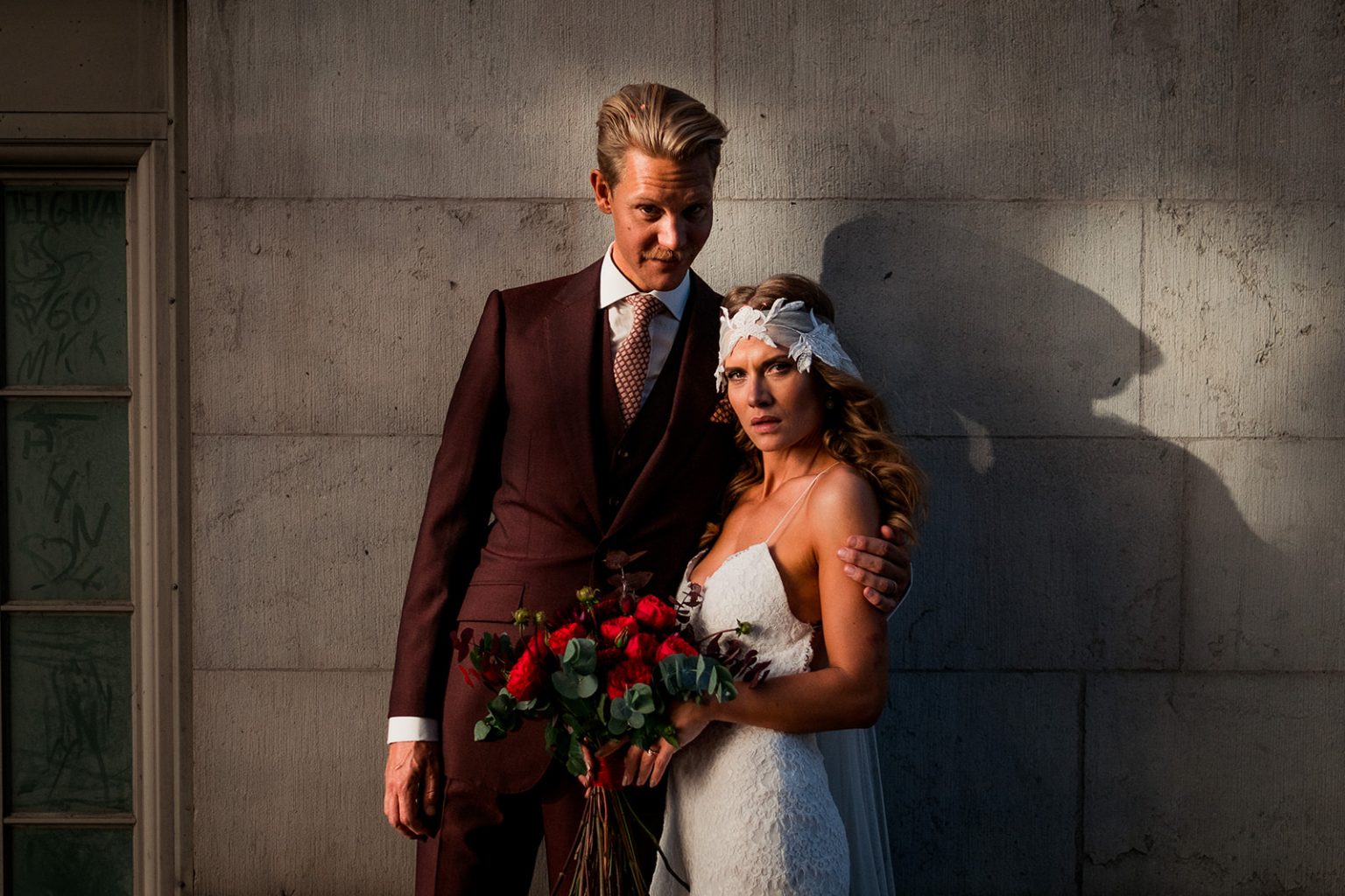 Bride and groom against a city wall in the evening light