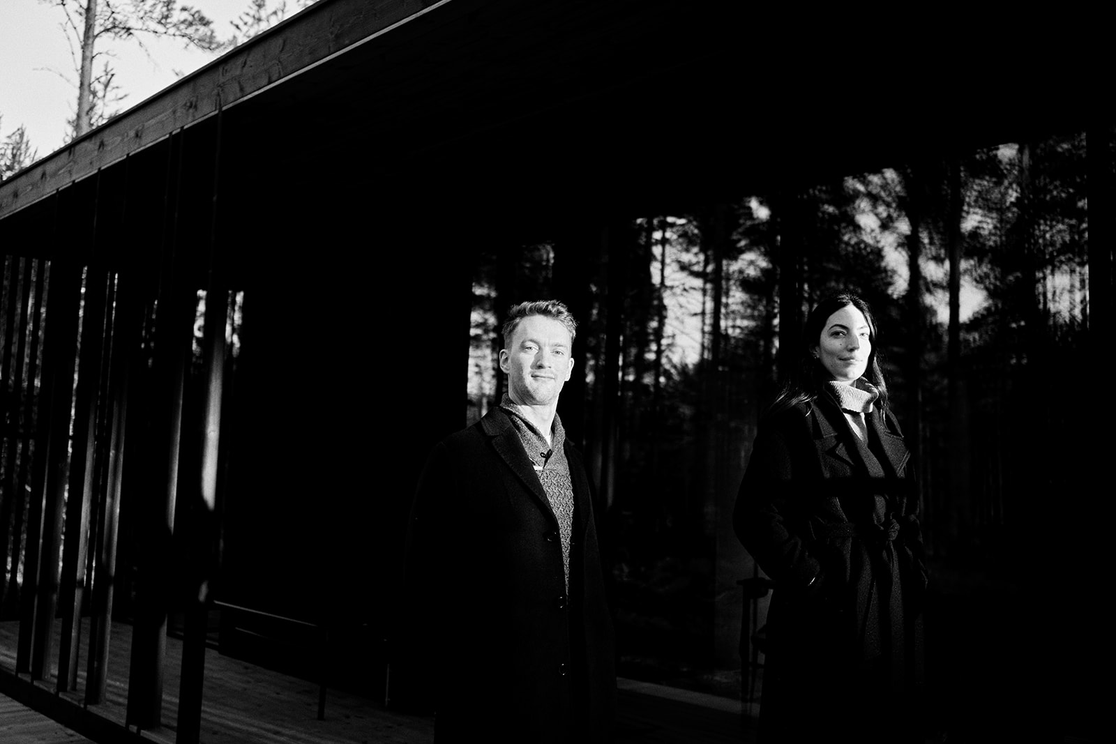 Engaged couple beside the black timber cabin at Hop Farm Beach on the Baltic coast, Söderhamn - Nordica Photography