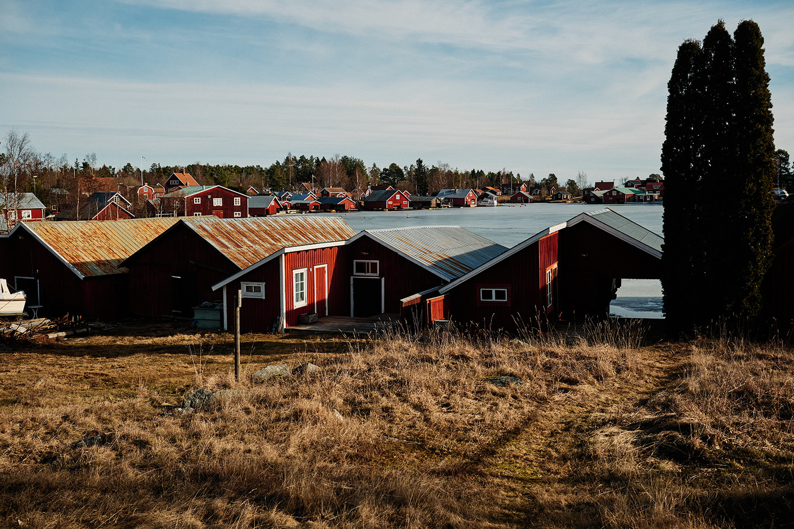 Red timber boathouses on the Baltic shore beside the Hop Farm Beach cabin, Söderhamn - Nordica Photography