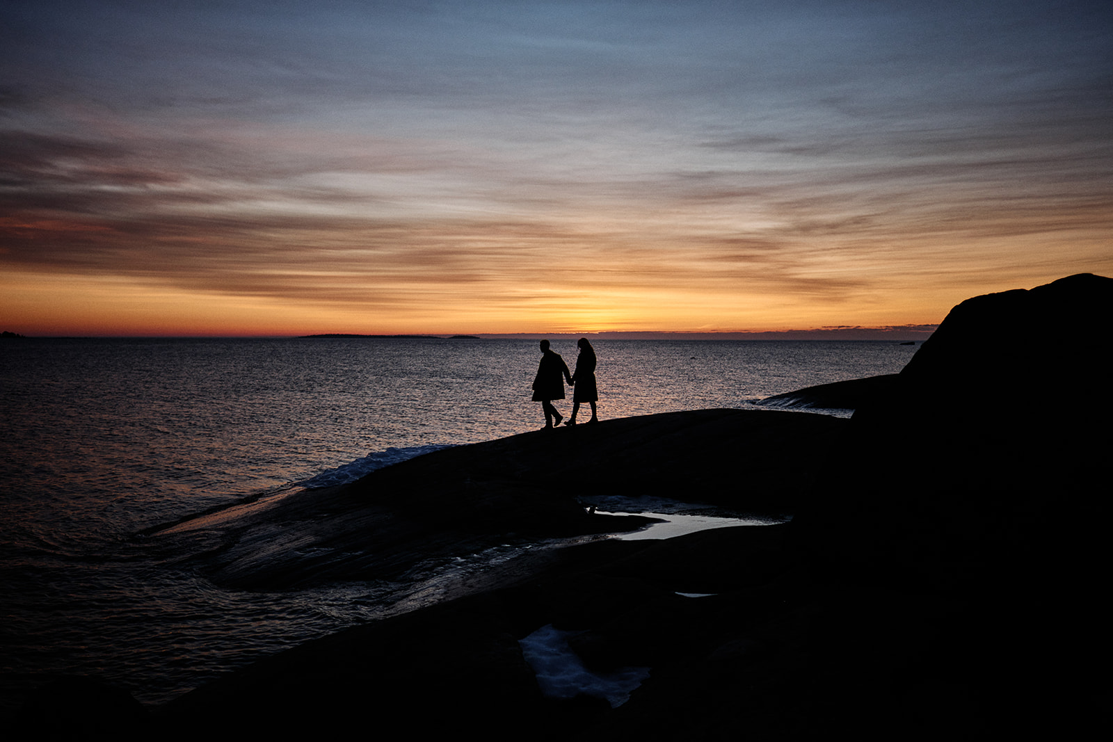 Couple silhouetted against the rising sun on the Baltic shore at Söderhamn, Sweden - Nordica Photography