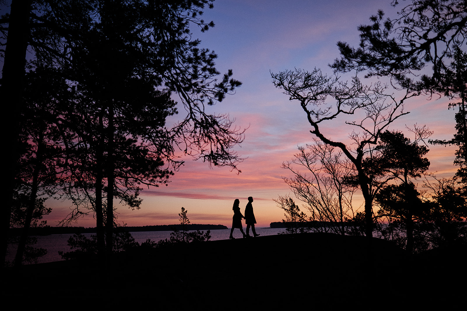Couple in silhouette on the Baltic shore at sunrise near the Hop Farm Beach cabin, Söderhamn - Nordica Photography