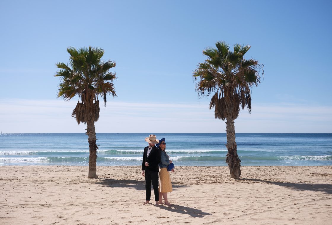 Adriana and Ondrej between two palms on the beach at Calpe, Valencia wedding photographer