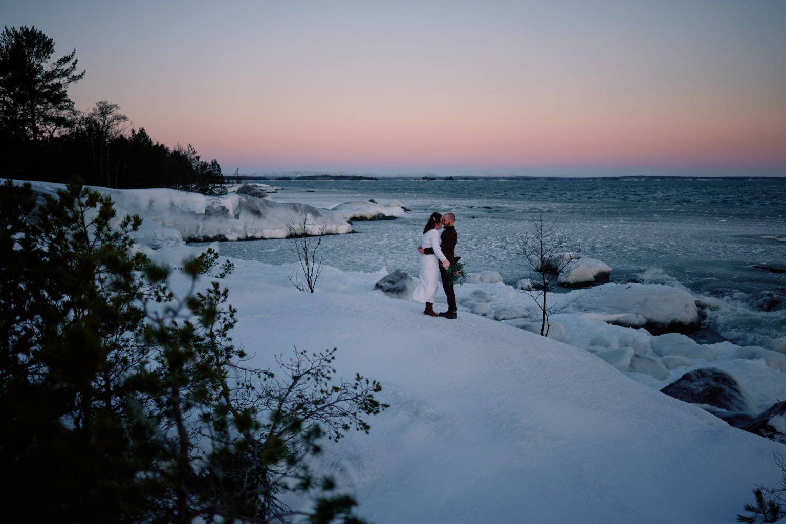 The couple out on the frozen shore, winter elopement photographer in Sweden