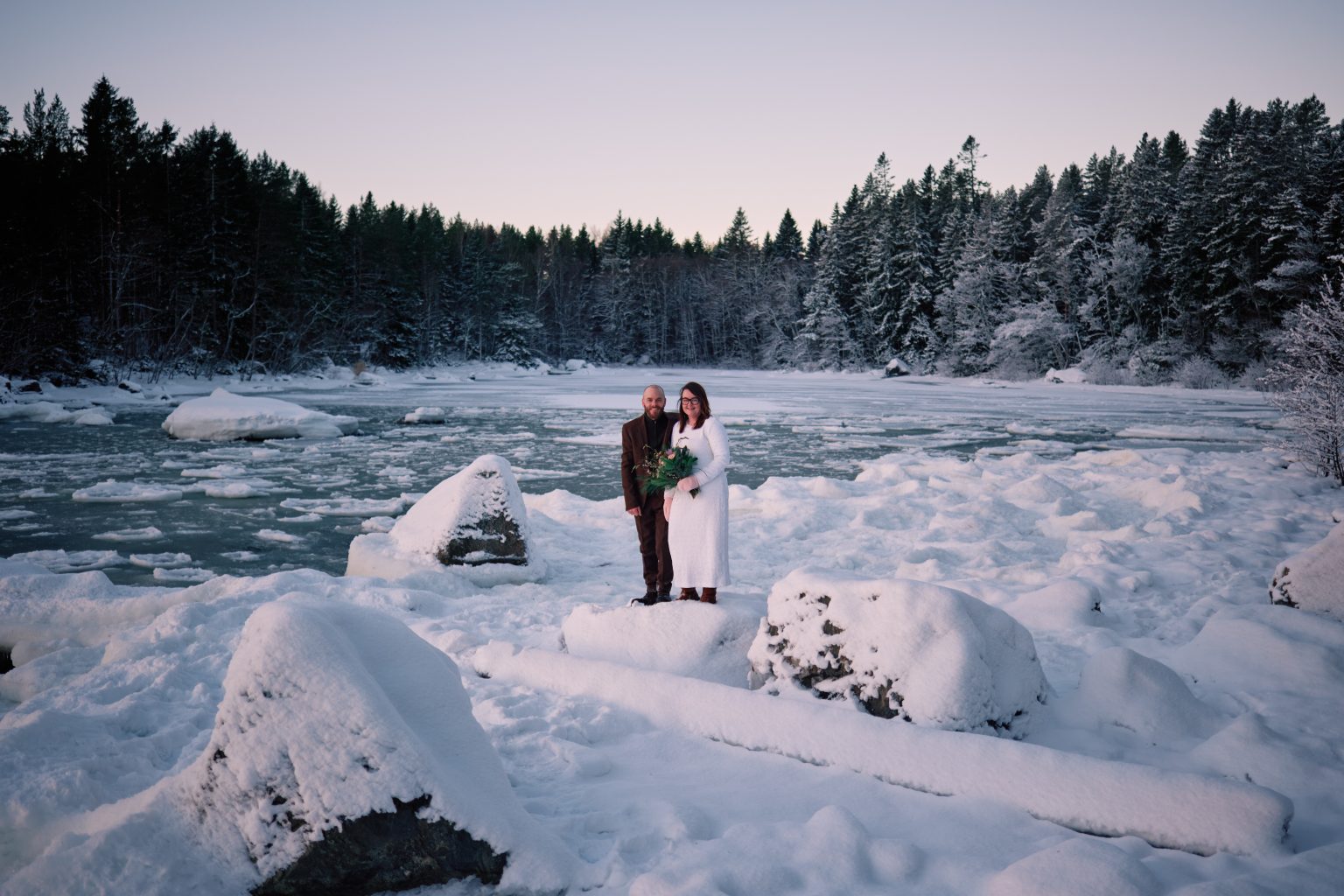 Sam and Rob among snowy rocks and pines, a Nordic elopement