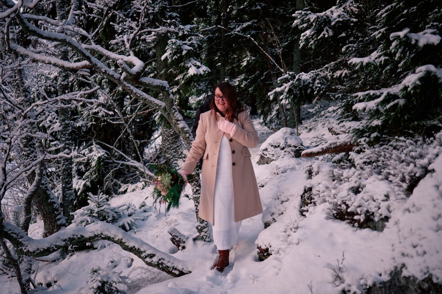 The bride walking through snowy pines, a Swedish winter elopement