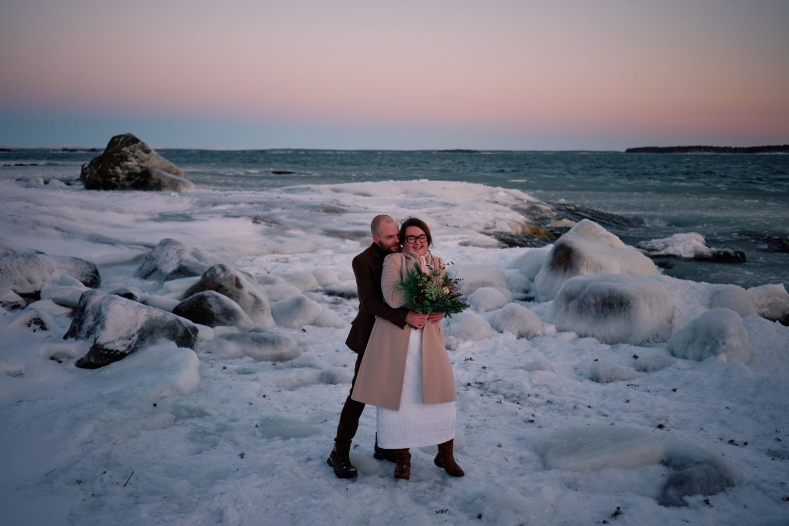 The couple on the snowy shore at dusk, elopement in Hälsingland