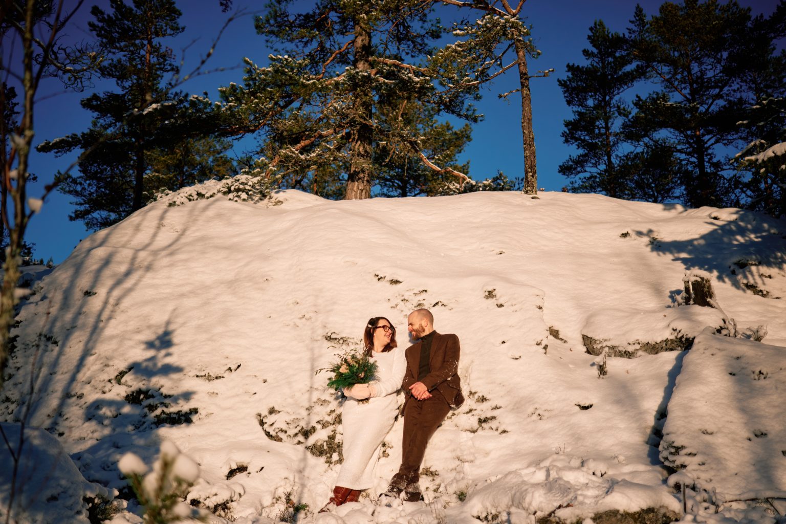 The couple small against the snow, elope in Sweden in winter