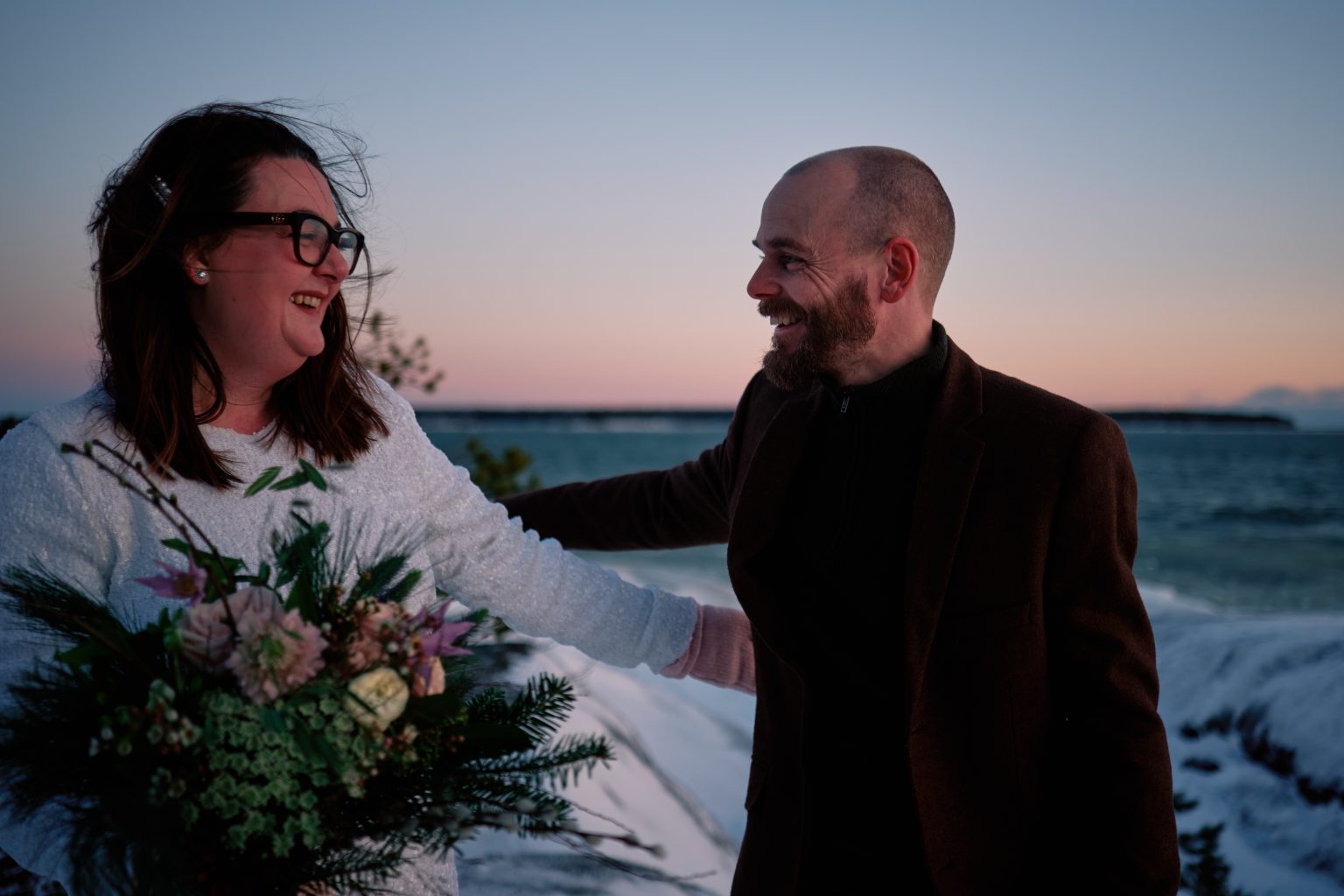 Sam and Rob together on the frozen coast, a Nordic winter elopement