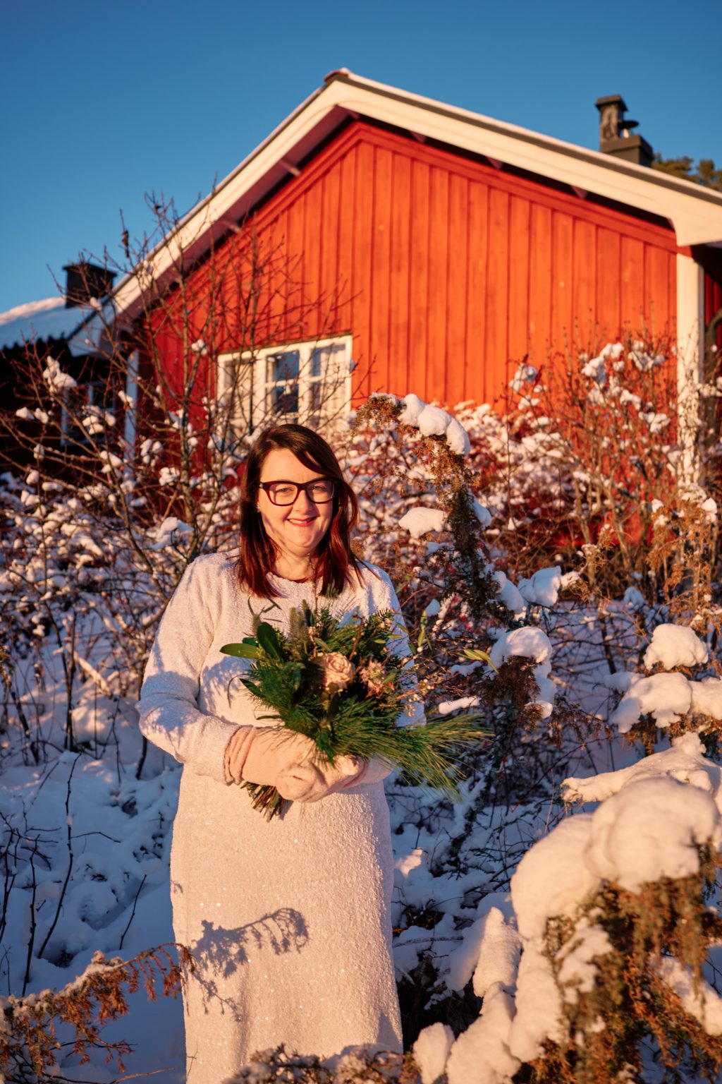 The bride by a Falu-red house in the snow, a Hälsingland winter elopement