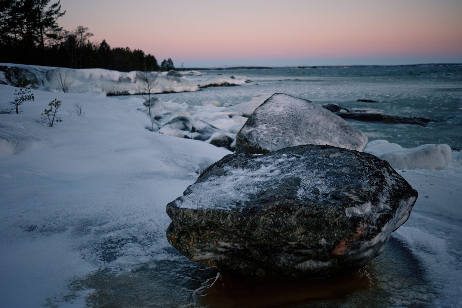 A snow-covered boulder on the frozen shore, Swedish winter elopement