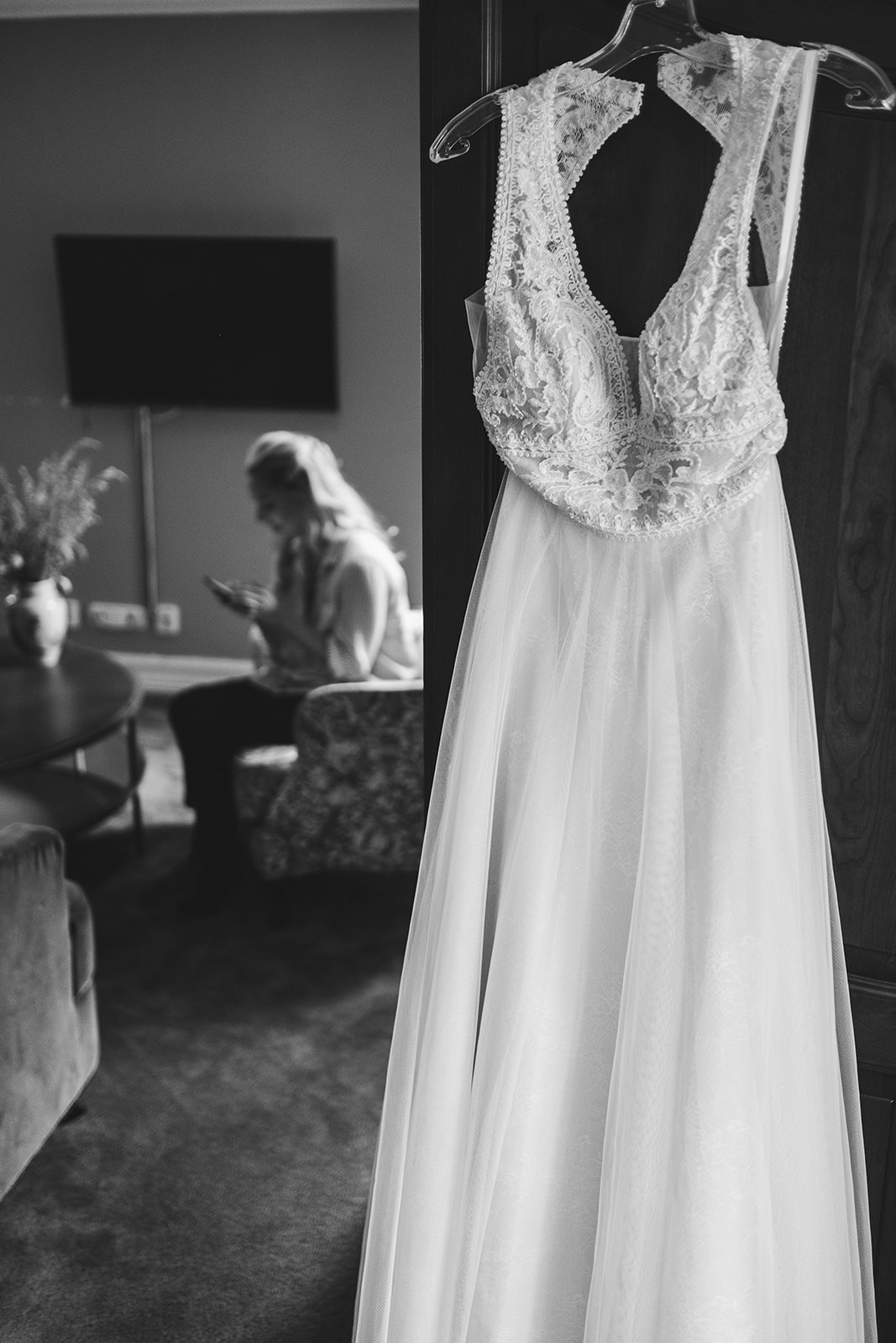 The wedding dress hanging in the hotel room, black and white