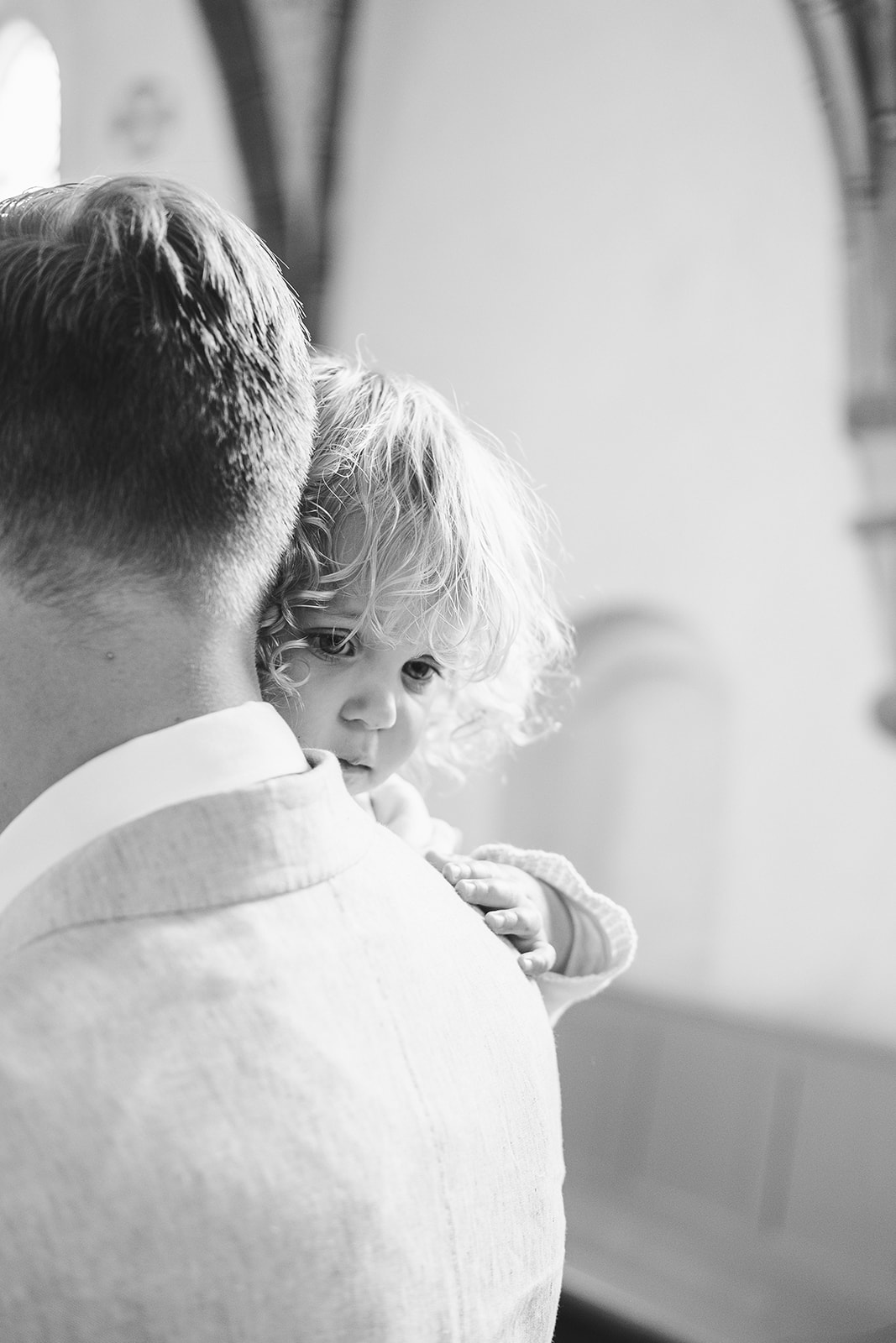 A child over a shoulder during the ceremony, black and white