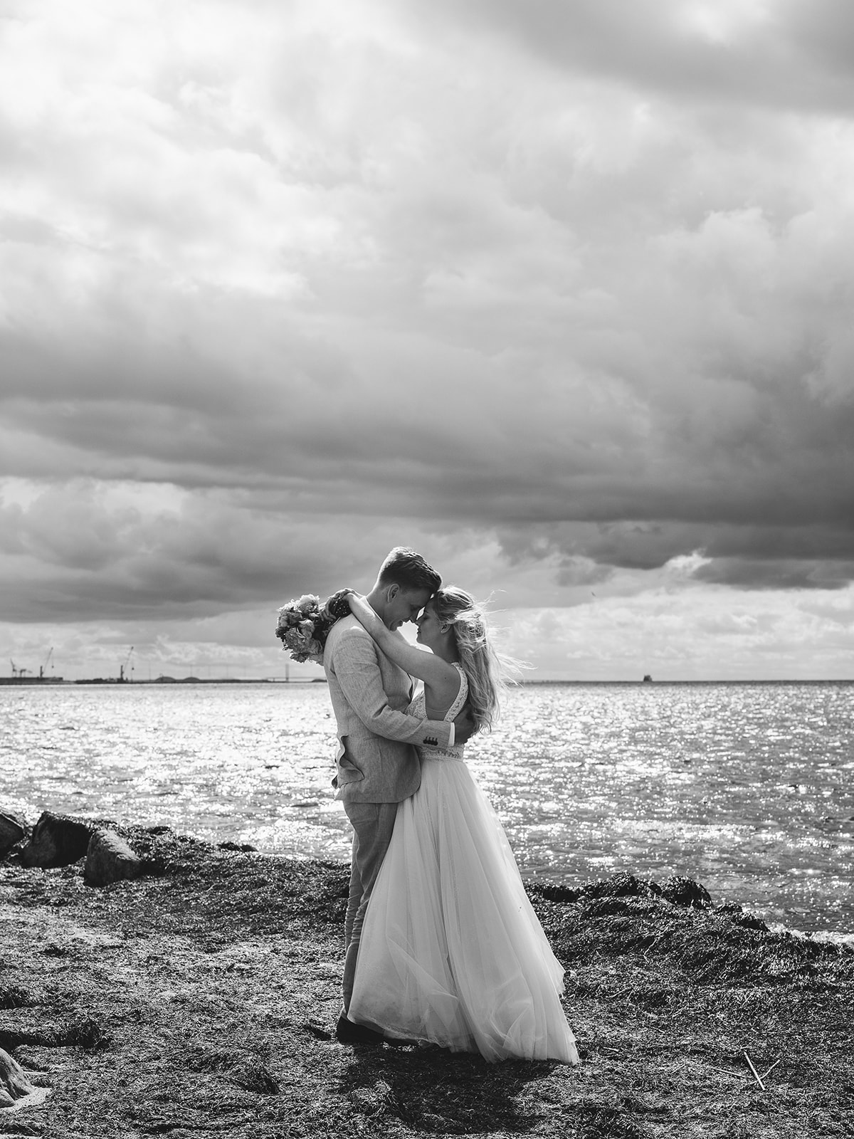 Bride and groom on the stony beach under a heavy sky
