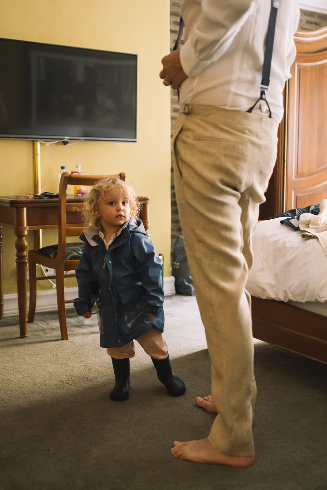 A small boy watching the groom get dressed