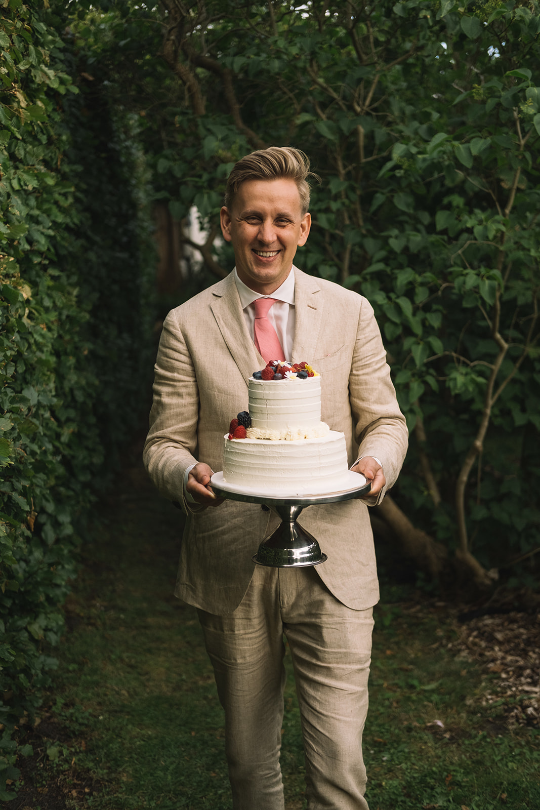 The groom carrying the wedding cake into the garden
